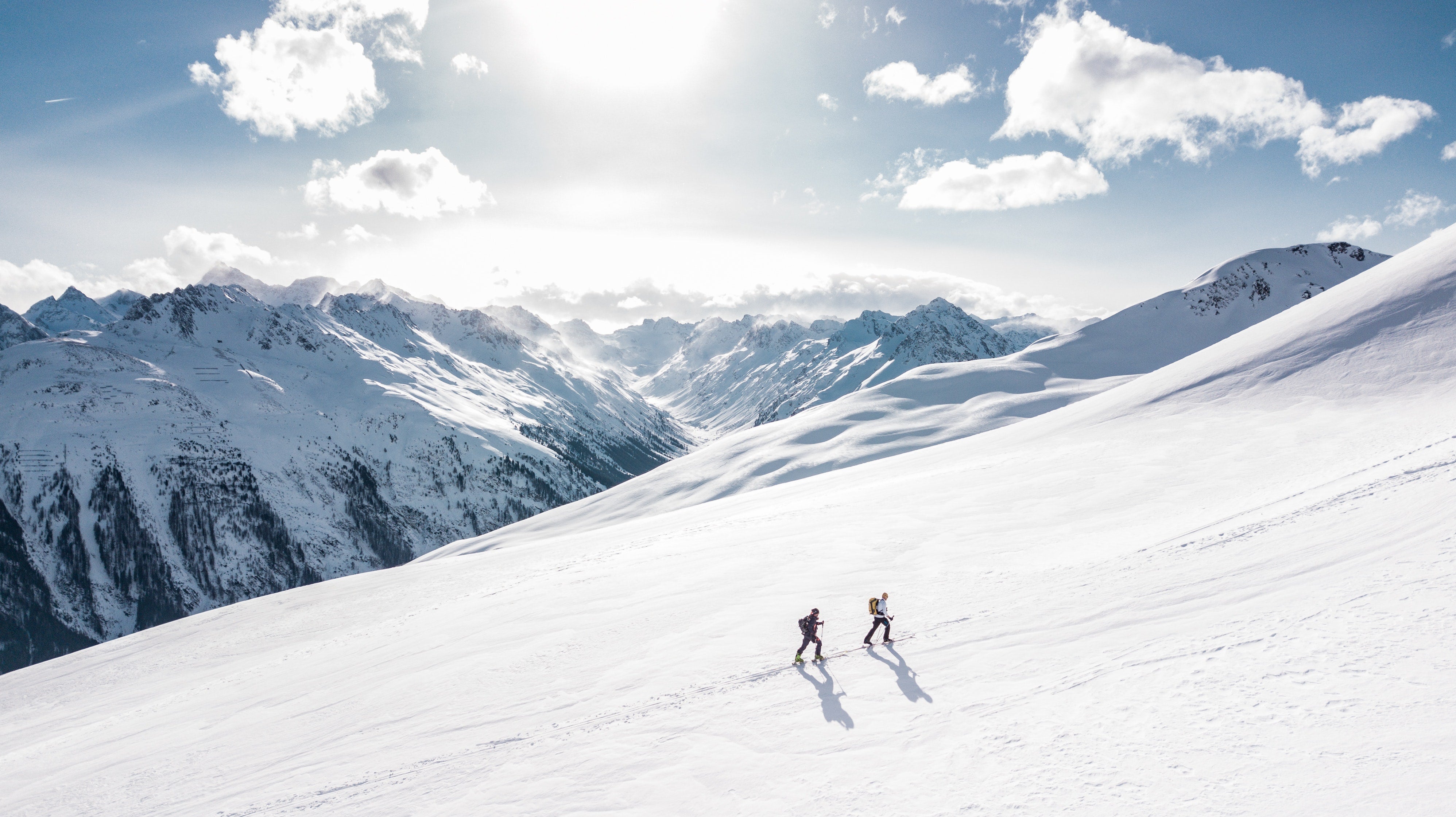 Two hikers trekking up the side of a snow covered mountain