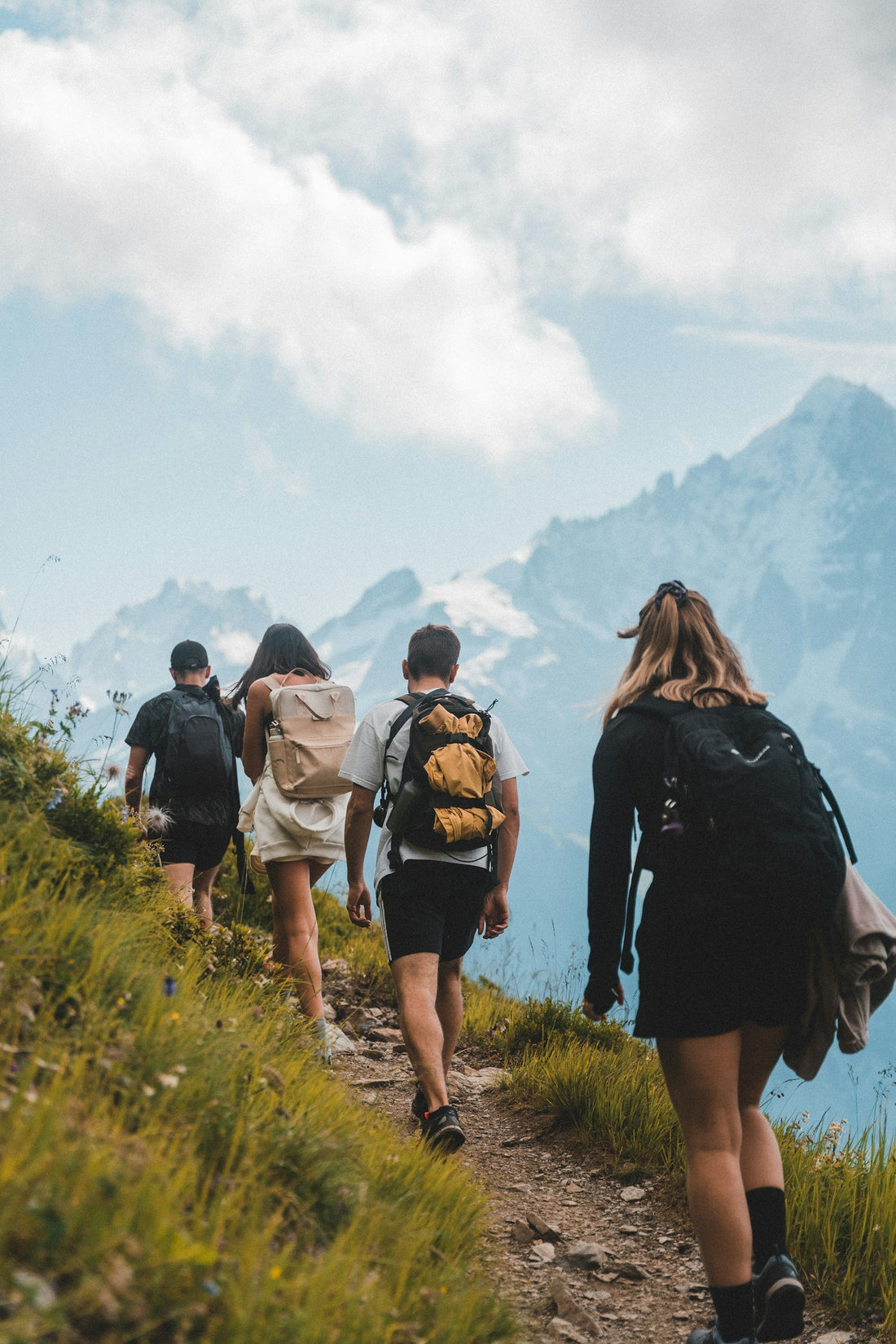 Group of hikers walking together across a grassy outdoor trail, staying active outdoors